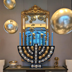 A decorative Hanukkah menorah-shaped balloon kit with gold, silver, and blue balloons, featuring a mirrored backdrop and a reflective floor.