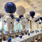 Decorated event room with blue, silver, and white balloons above tables set for a meal.