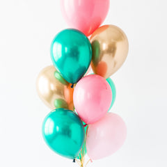 Bouquet of colorful balloons including pink, green, and gold on a white background