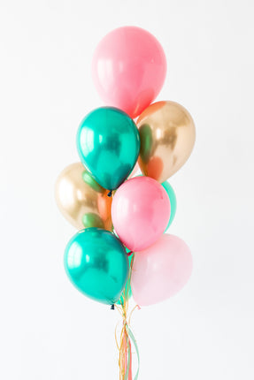 Bouquet of colorful balloons including pink, green, and gold on a white background