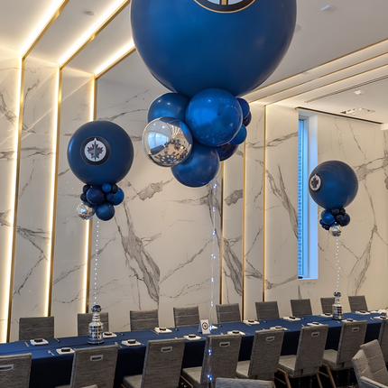 Decorative setup with blue balloons featuring a logo in a formal event room.