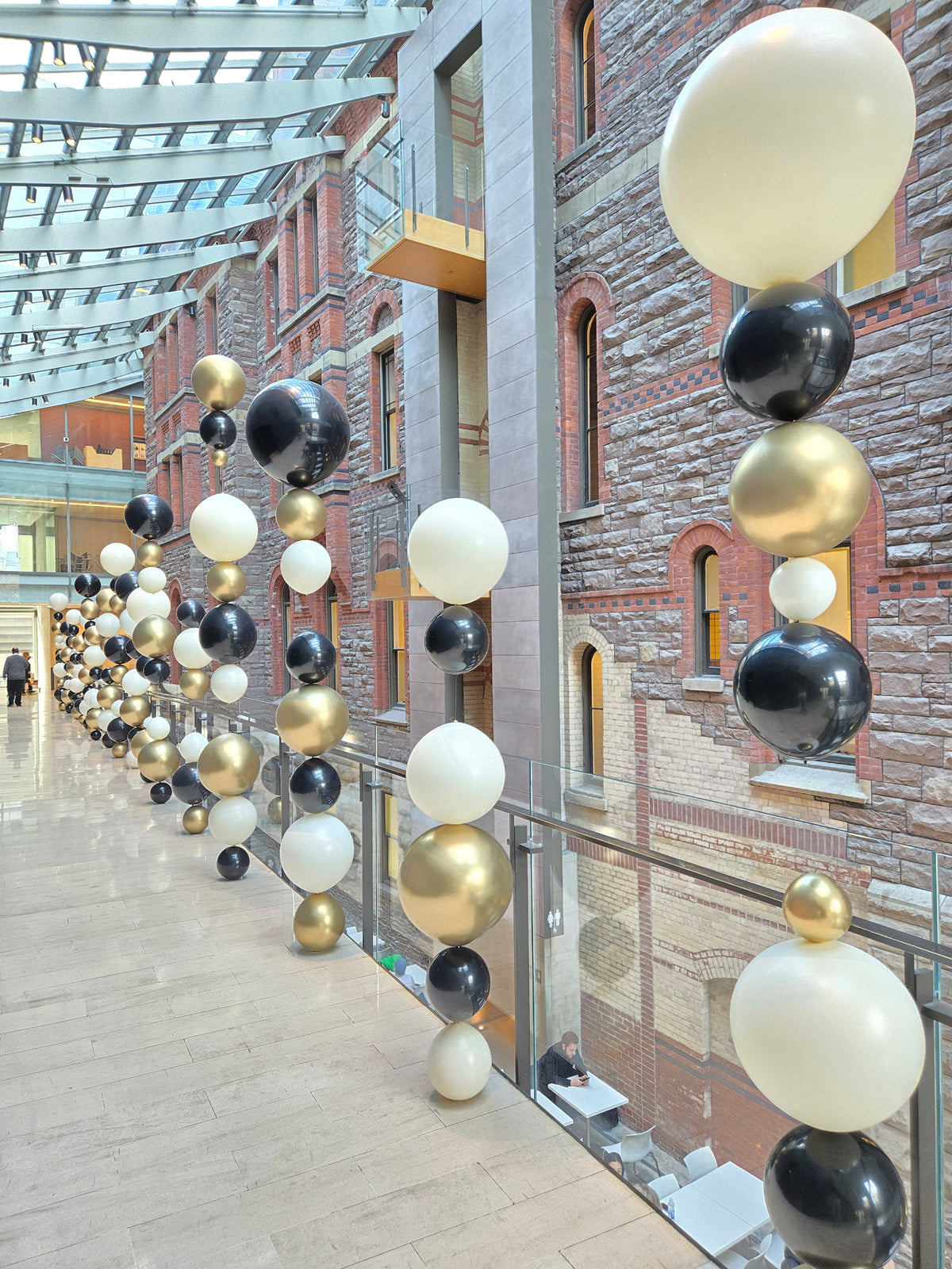 Decorative arrangement of black, white, and gold balloons hanging from a ceiling.