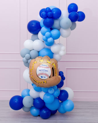 A balloon garland featuring a variety of blue and white balloons shaped like baseballs and a baseball glove, with a prominent baseball-themed balloon at the center.