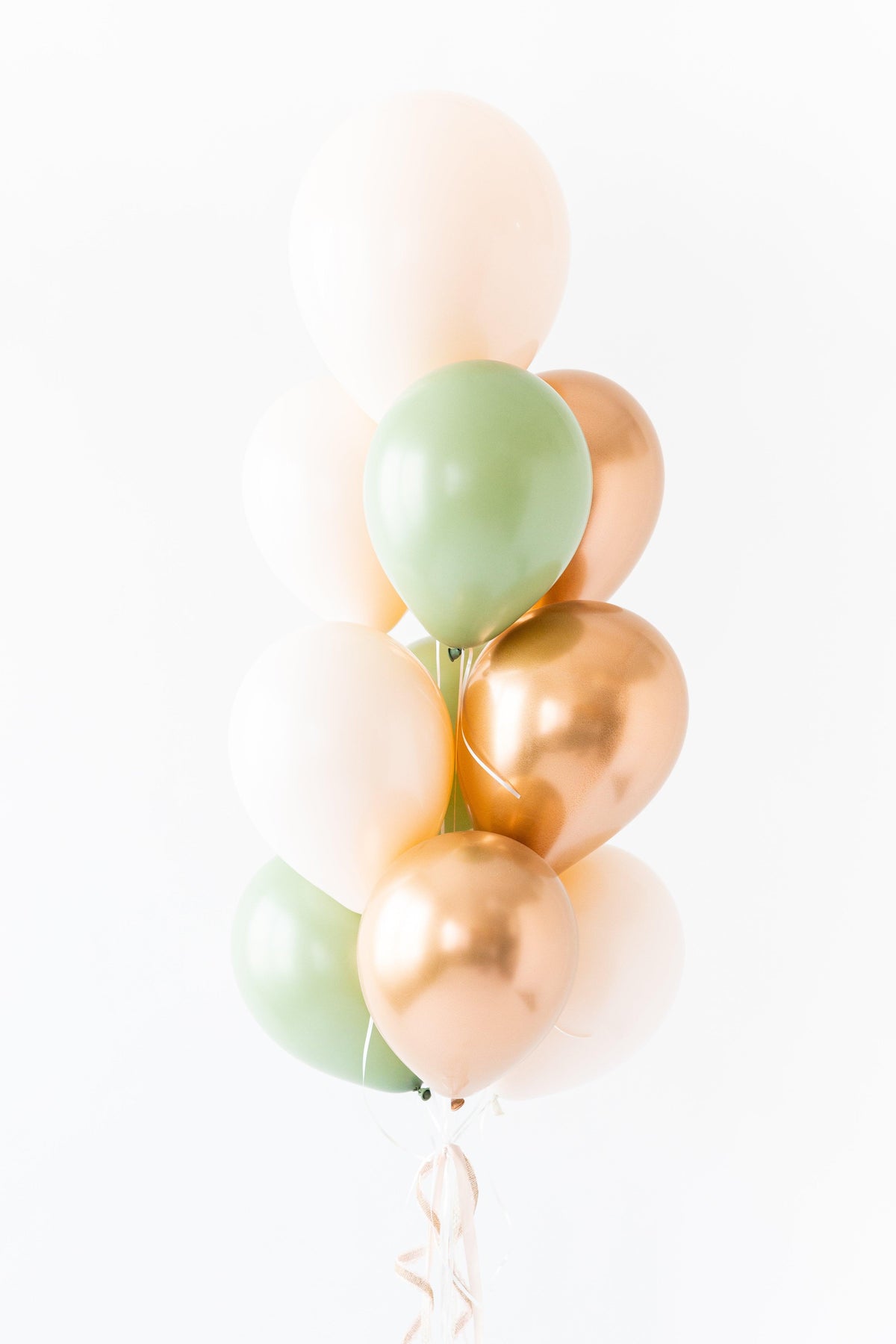 A bunch of round balloons in shades of pink, green, and gold, tied together with a string.